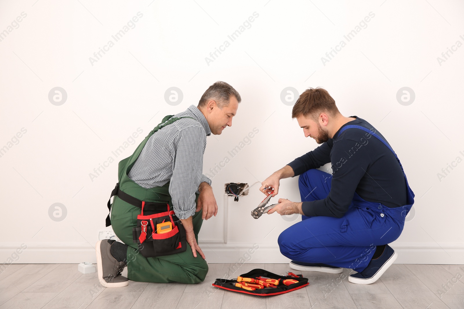 Photo of Electrician and apprentice working with wires indoors