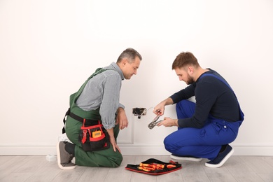 Photo of Electrician and apprentice working with wires indoors
