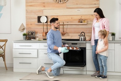 Photo of Man treating family with oven baked cookies in kitchen