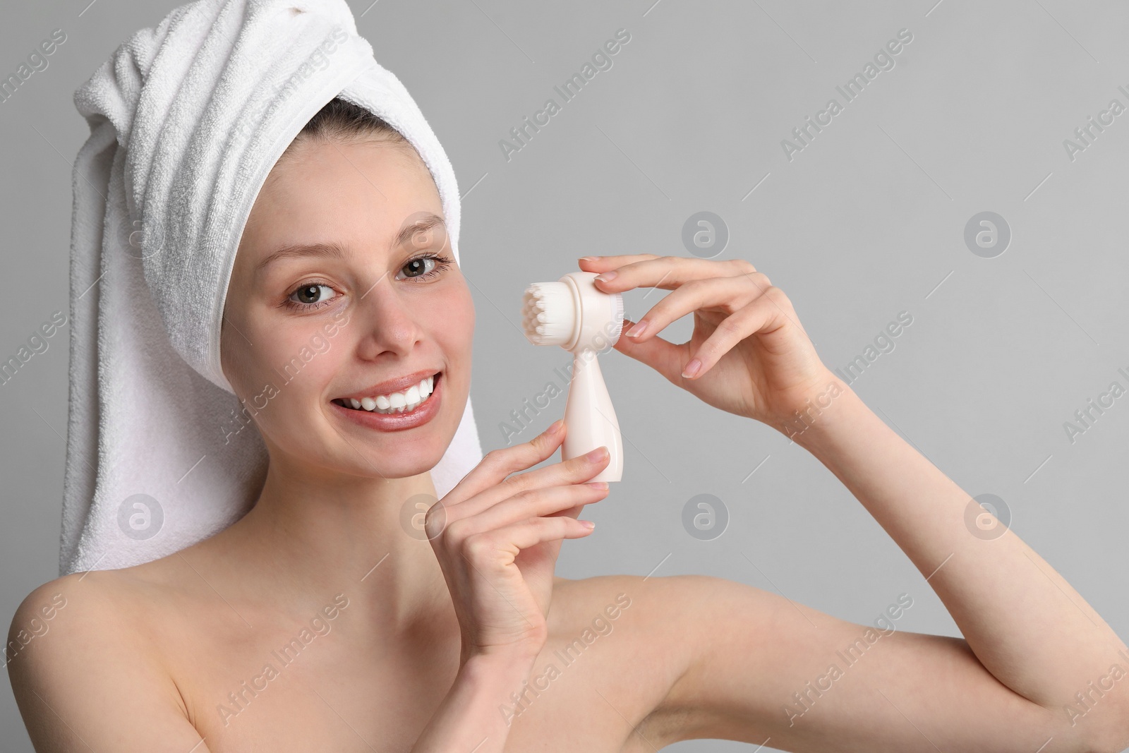 Photo of Washing face. Young woman with cleansing brush on grey background