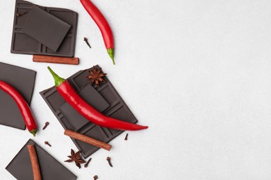 Photo of Delicious chocolate, fresh red chili peppers and spices on white table, flat lay. Space for text