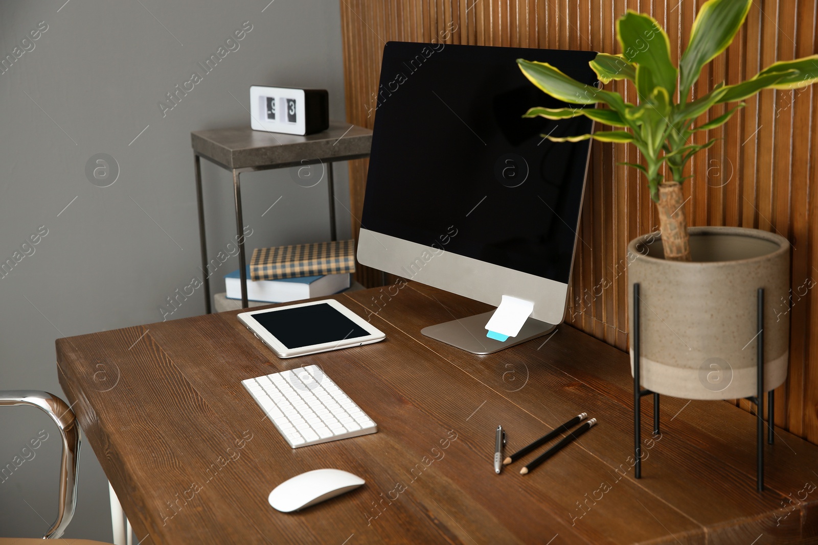 Photo of Stylish workplace with modern computer near wooden wall. Space for text