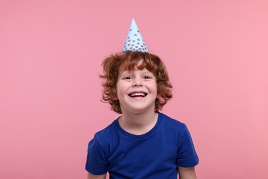 Happy little boy in party hat on pink background