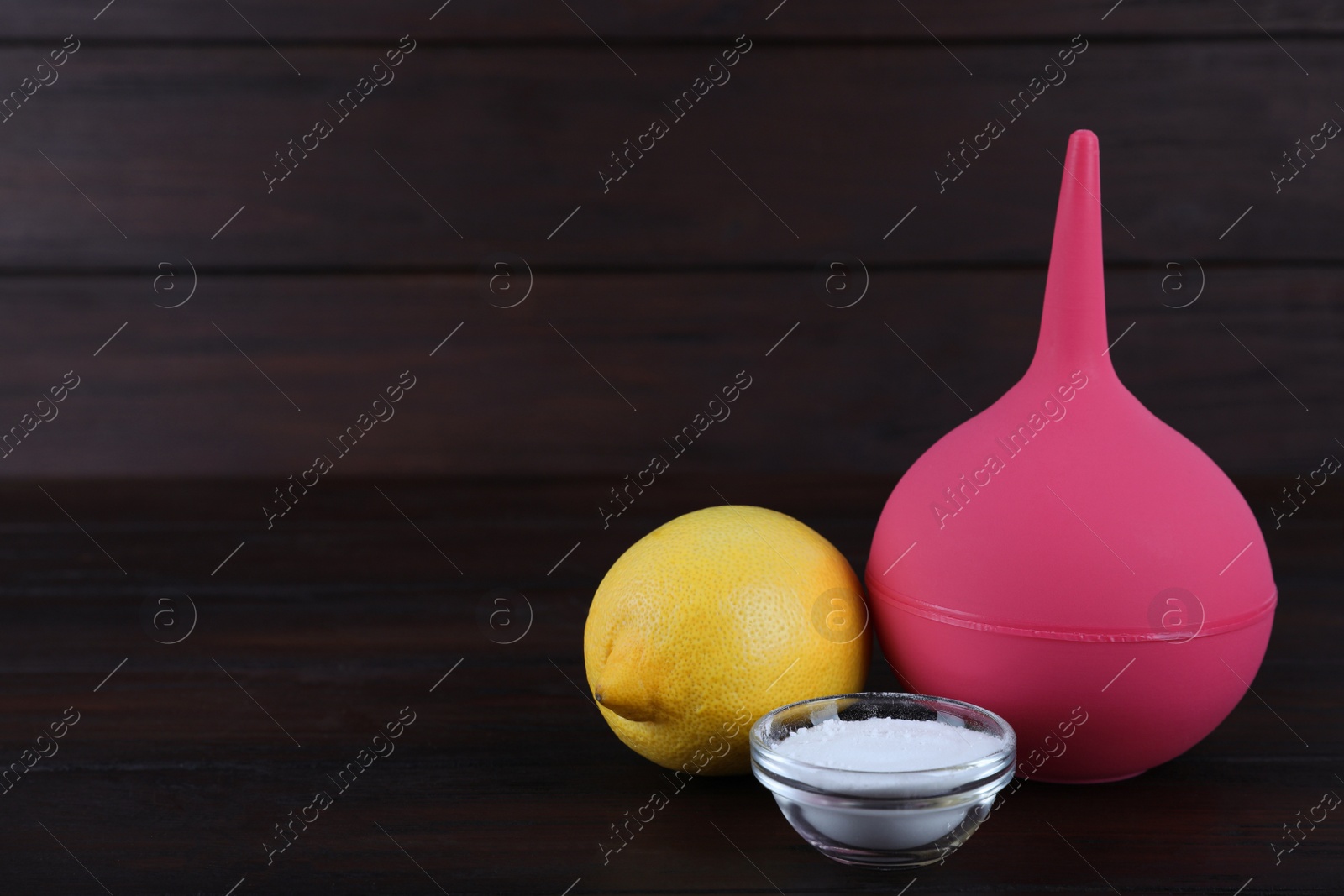 Photo of Enema, lemon and bowl of salt on wooden table, space for text. Medical treatment