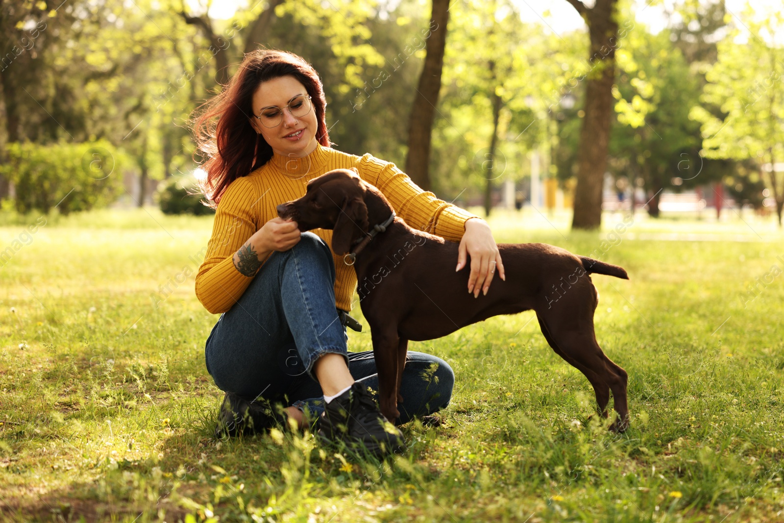 Photo of Woman with her cute German Shorthaired Pointer dog in park on spring day