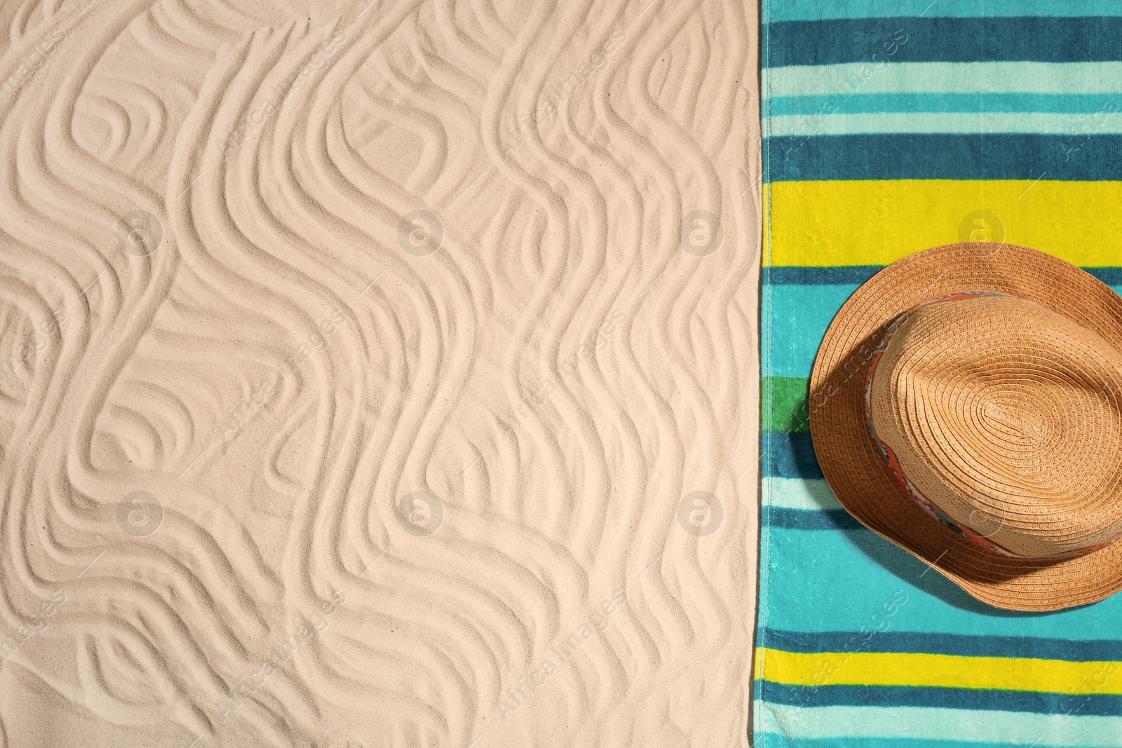 Photo of Bright towel and hat on sand, top view with space for text. Beach objects