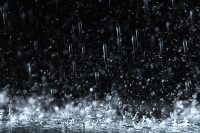 Photo of Heavy rain falling down on ground against dark background