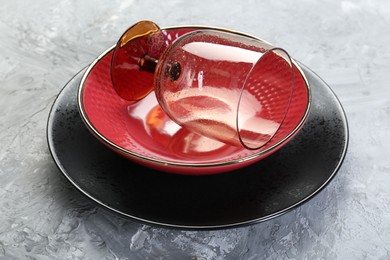 Photo of Clean plates, bowl and glass on gray textured table, closeup
