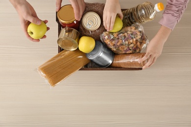 Photo of Volunteers taking food out of donation box on table, top view