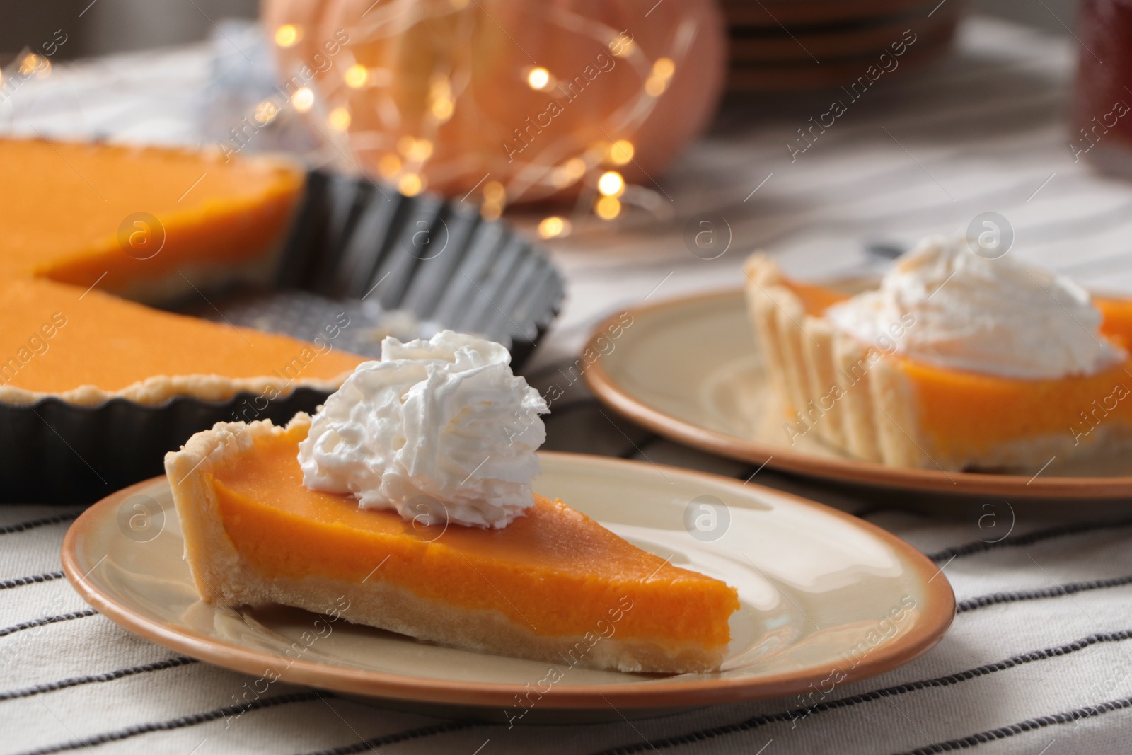 Photo of Fresh homemade pumpkin pie with whipped cream on table