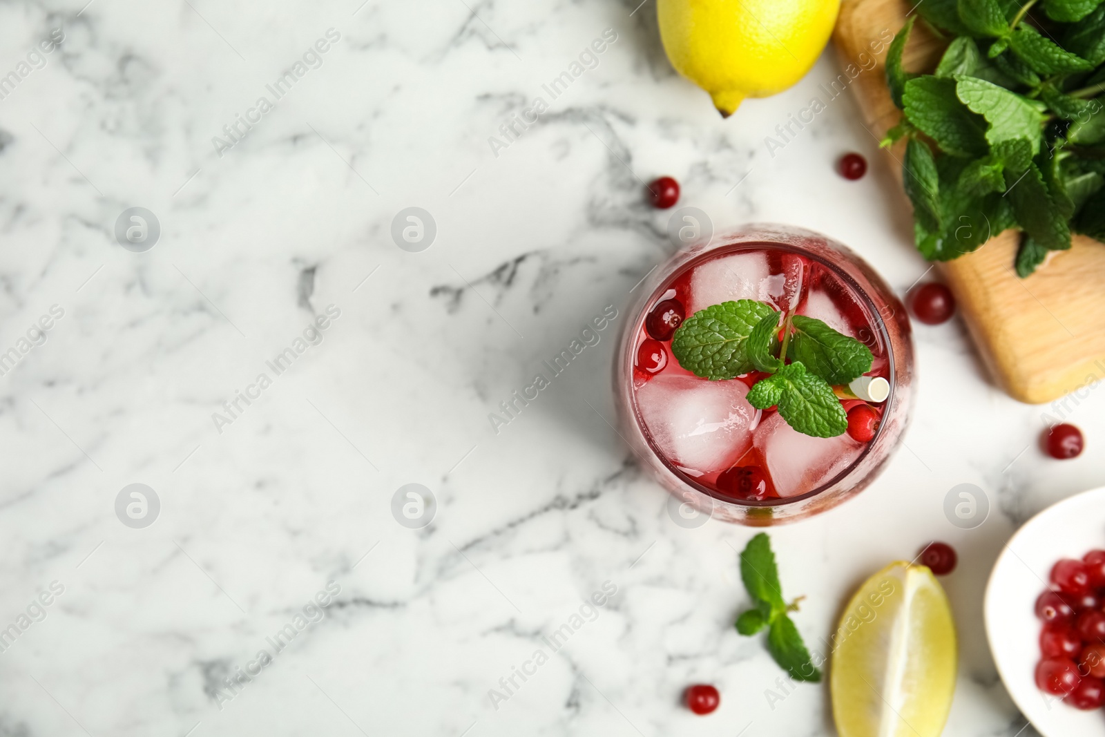 Photo of Tasty refreshing cranberry cocktail and fresh ingredients on white marble table, flat lay. Space for text