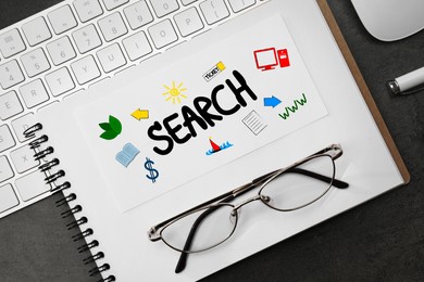Image of SEO concept. Notebook with word SEARCH and different drawings, computer keyboard and glasses on black table, flat lay