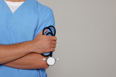 Photo of Doctor with stethoscope on light grey background, closeup. Space for text