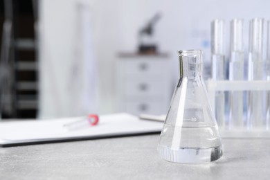 Photo of Laboratory analysis. Flask and test tubes on light grey table indoors, space for text