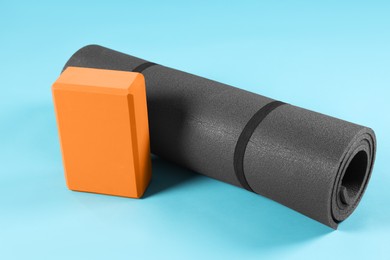 Photo of Exercise mat and yoga block on light blue background