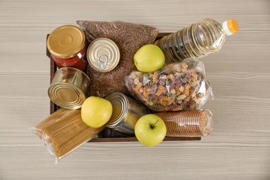 Photo of Donation box with food on wooden table, top view