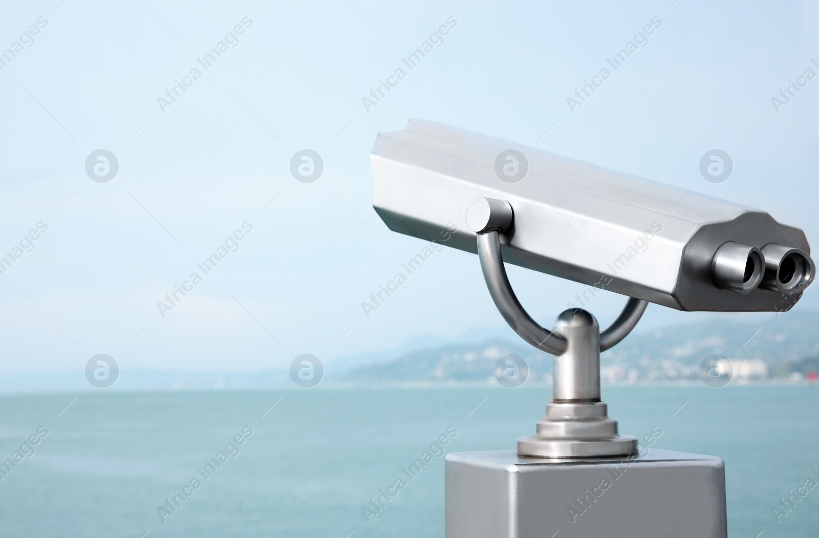 Photo of Metal tower viewer installed near sea, space for text. Mounted binoculars