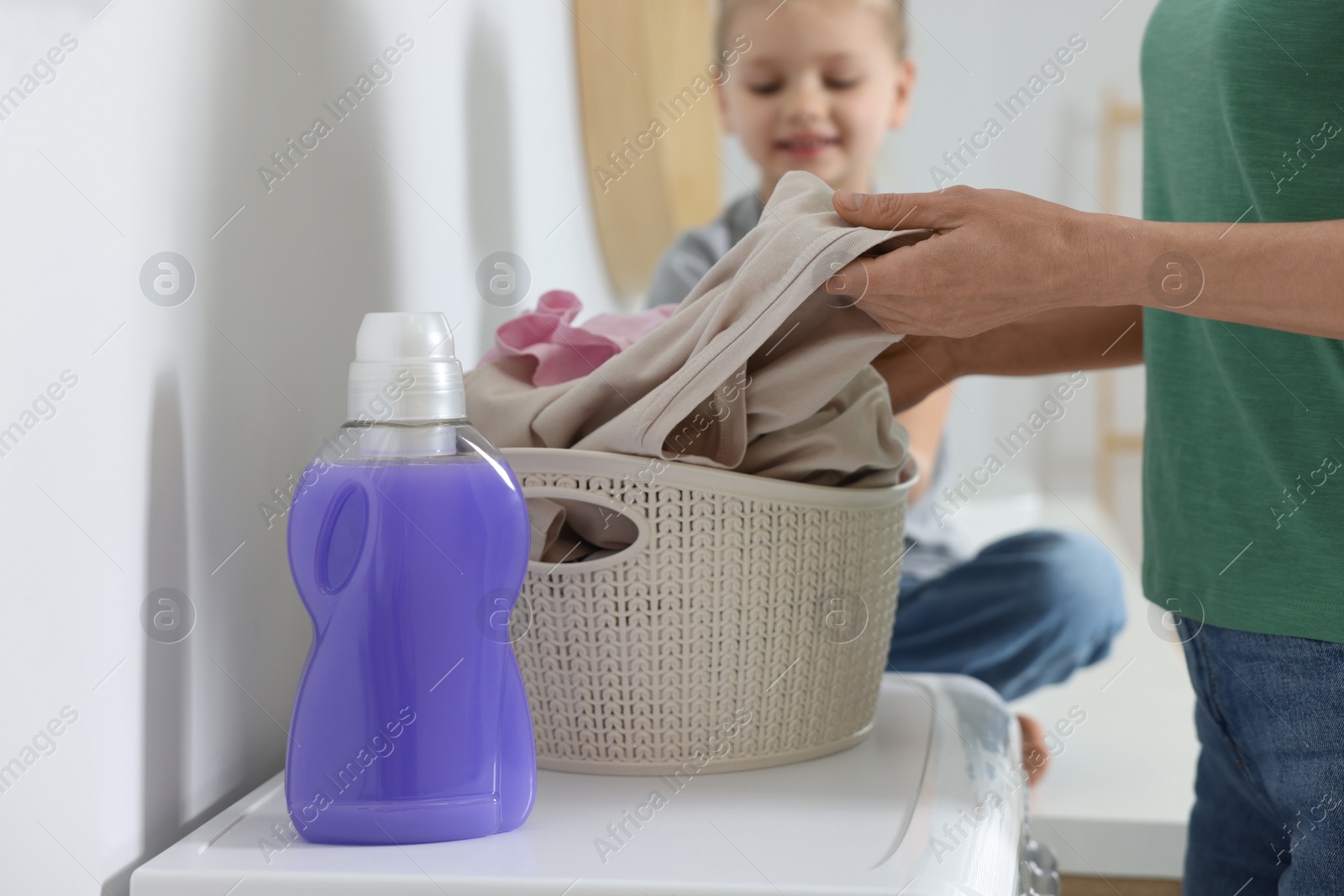 Photo of Mother and daughter taking out dirty clothes from basket indoors, selective focus