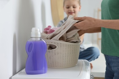 Photo of Mother and daughter taking out dirty clothes from basket indoors, selective focus