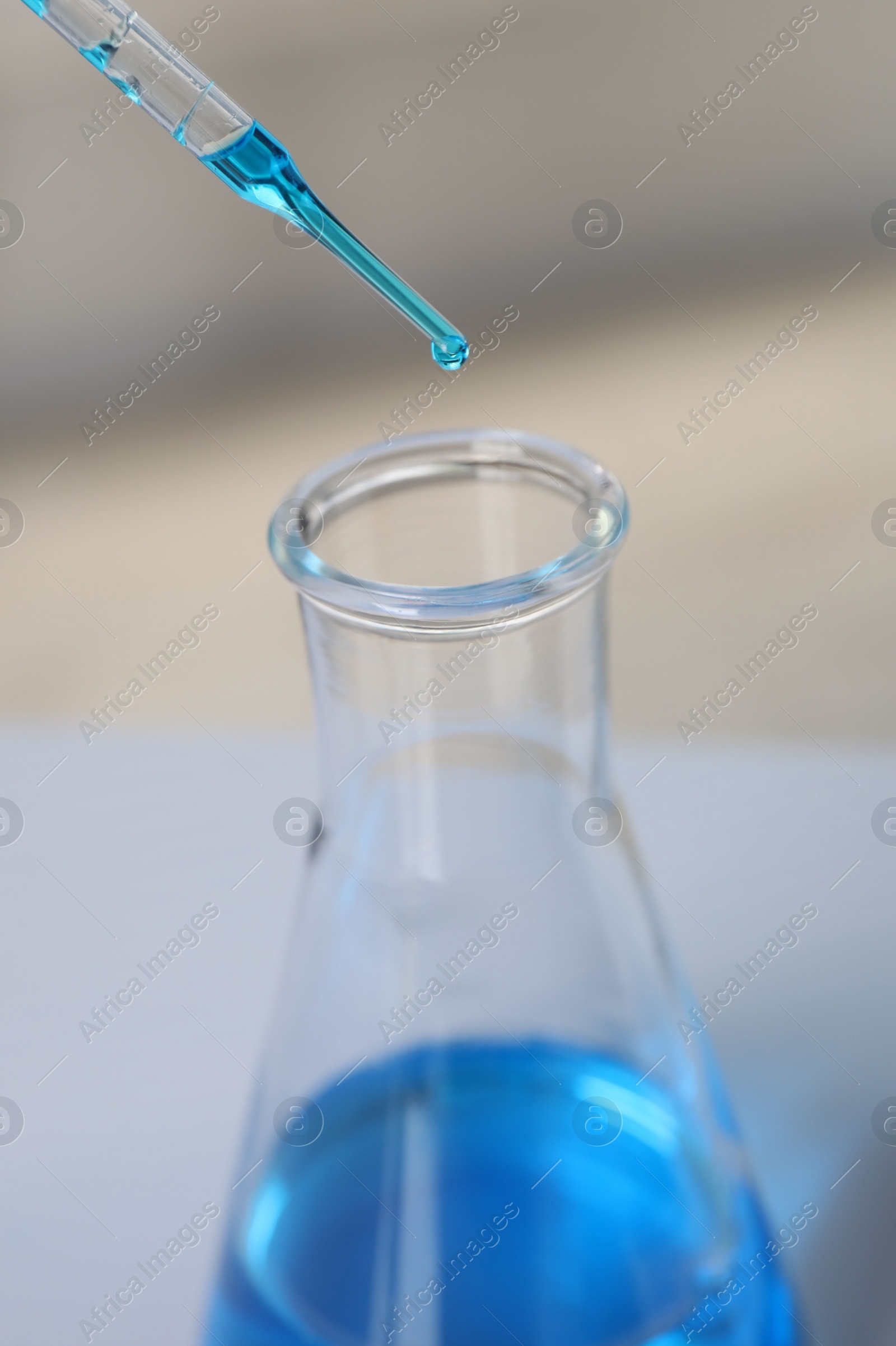 Photo of Laboratory analysis. Dripping blue liquid into flask on table, closeup