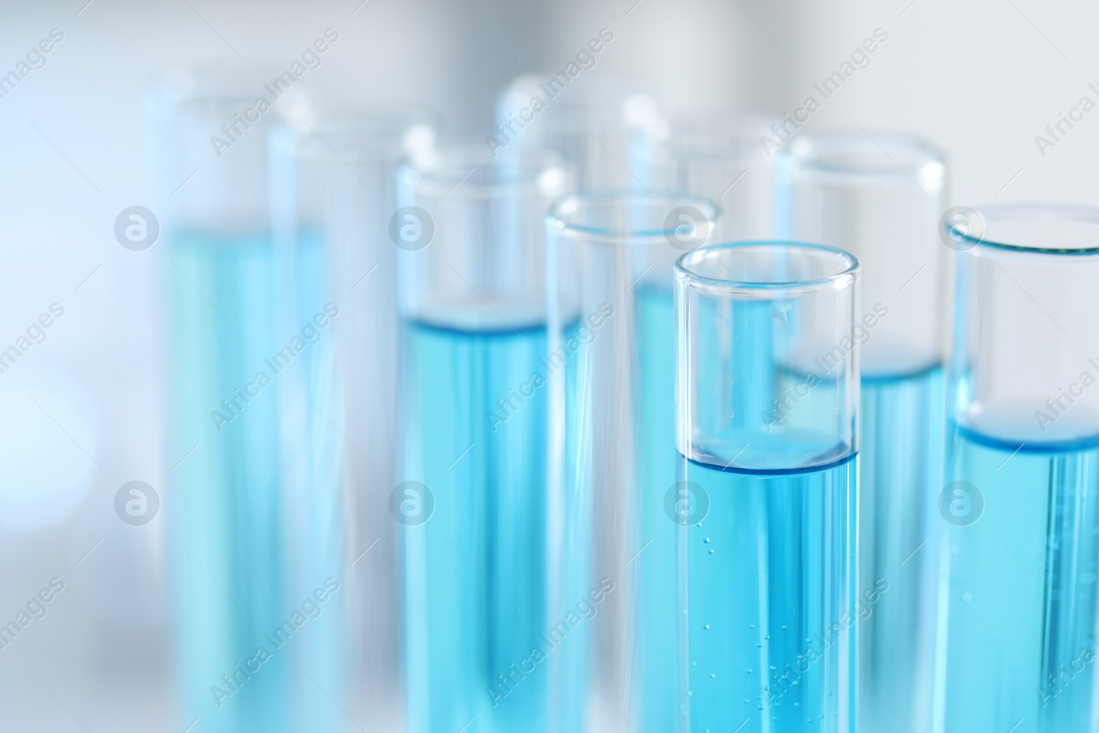 Photo of Test tubes with light blue liquid in laboratory, closeup. Space for text