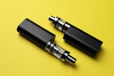 Photo of New reusable electronic cigarettes on yellow background