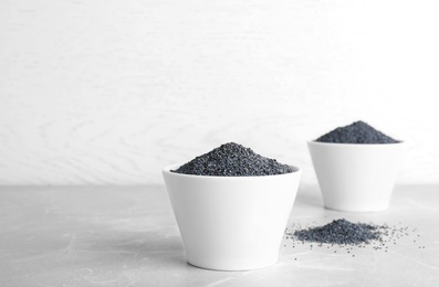 Poppy seeds in bowl on table against light background. Space for text