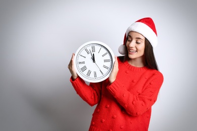 Photo of Woman in Santa hat with clock on white background, space for text. New Year countdown