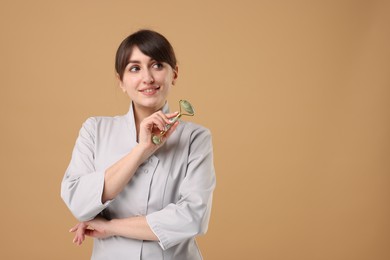 Cosmetologist with facial roller on beige background, space for text