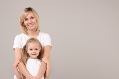 Family portrait of happy mother and daughter on grey background. Space for text