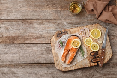 Fresh raw salmon steak with seasonings on wooden background, top view