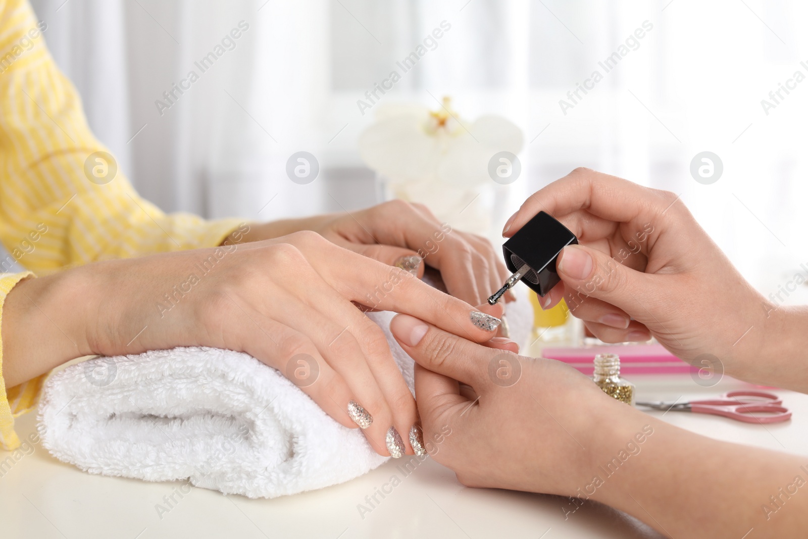 Photo of Manicurist painting client's nails with polish in salon, closeup