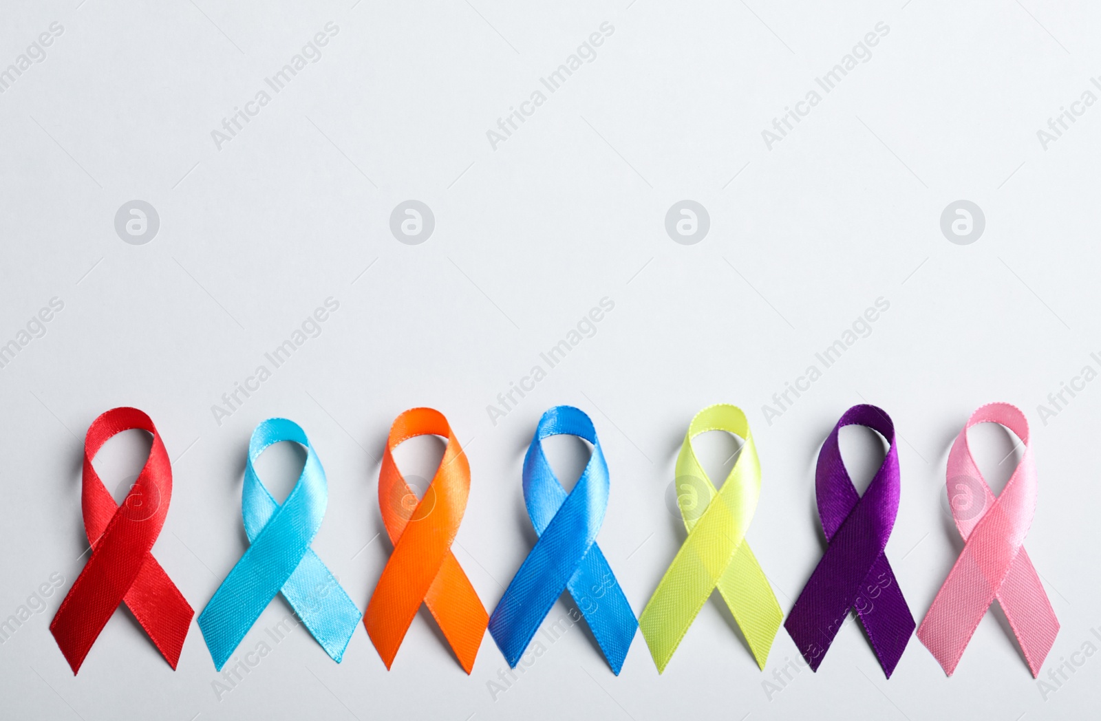 Photo of Different colorful ribbons on white background, flat lay with space for text. World Cancer Day