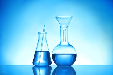 Photo of Laboratory glassware with liquid samples for analysis on blue background