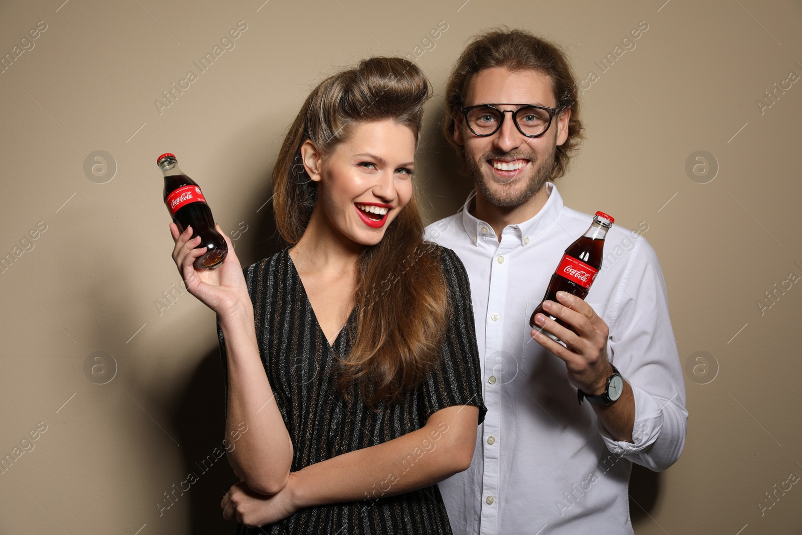 Photo of MYKOLAIV, UKRAINE - NOVEMBER 28, 2018: Young couple with bottles of Coca-Cola on color background