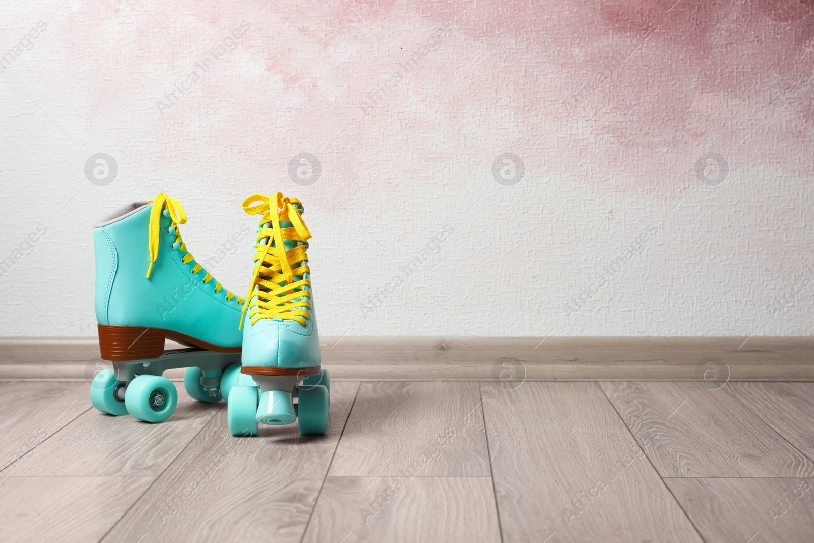 Photo of Vintage roller skates on floor near color wall. Space for text