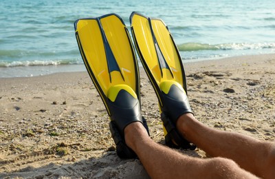 Photo of Man in flippers near sea on beach, closeup