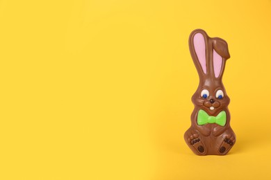 Photo of Chocolate bunny on yellow background, space for text. Easter celebration