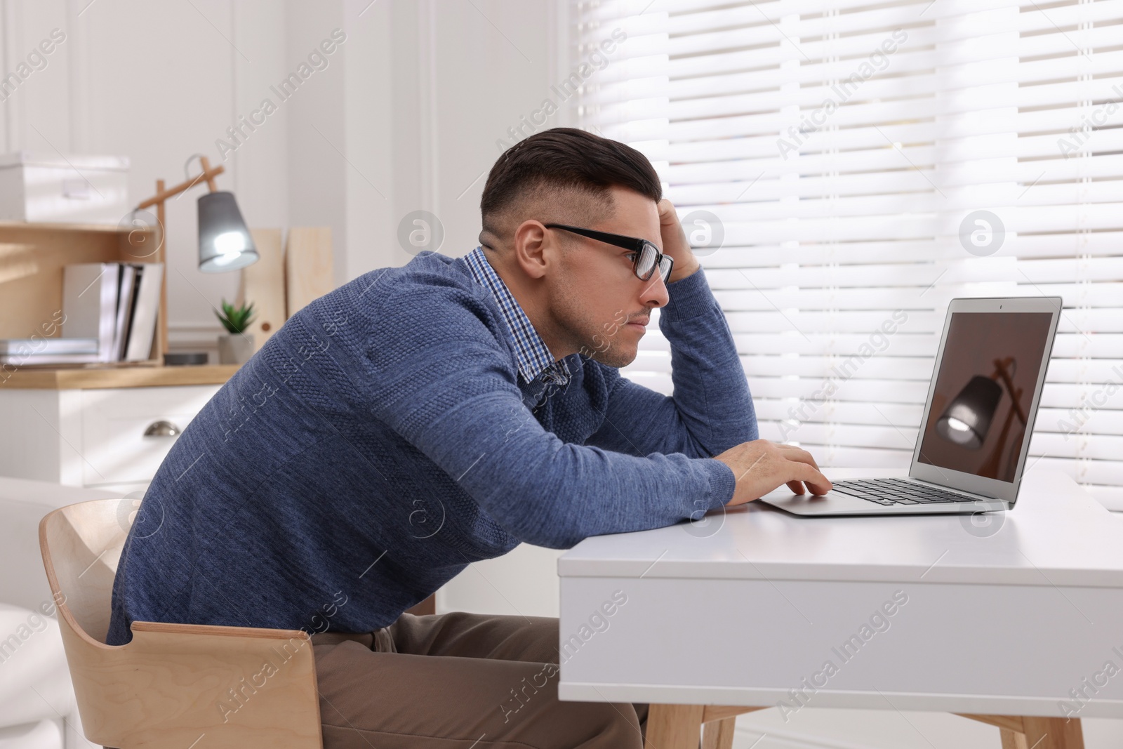 Photo of Man with poor posture using laptop at table indoors