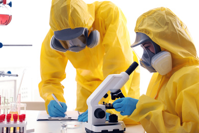 Scientists in chemical protective suits working at laboratory. Virus research