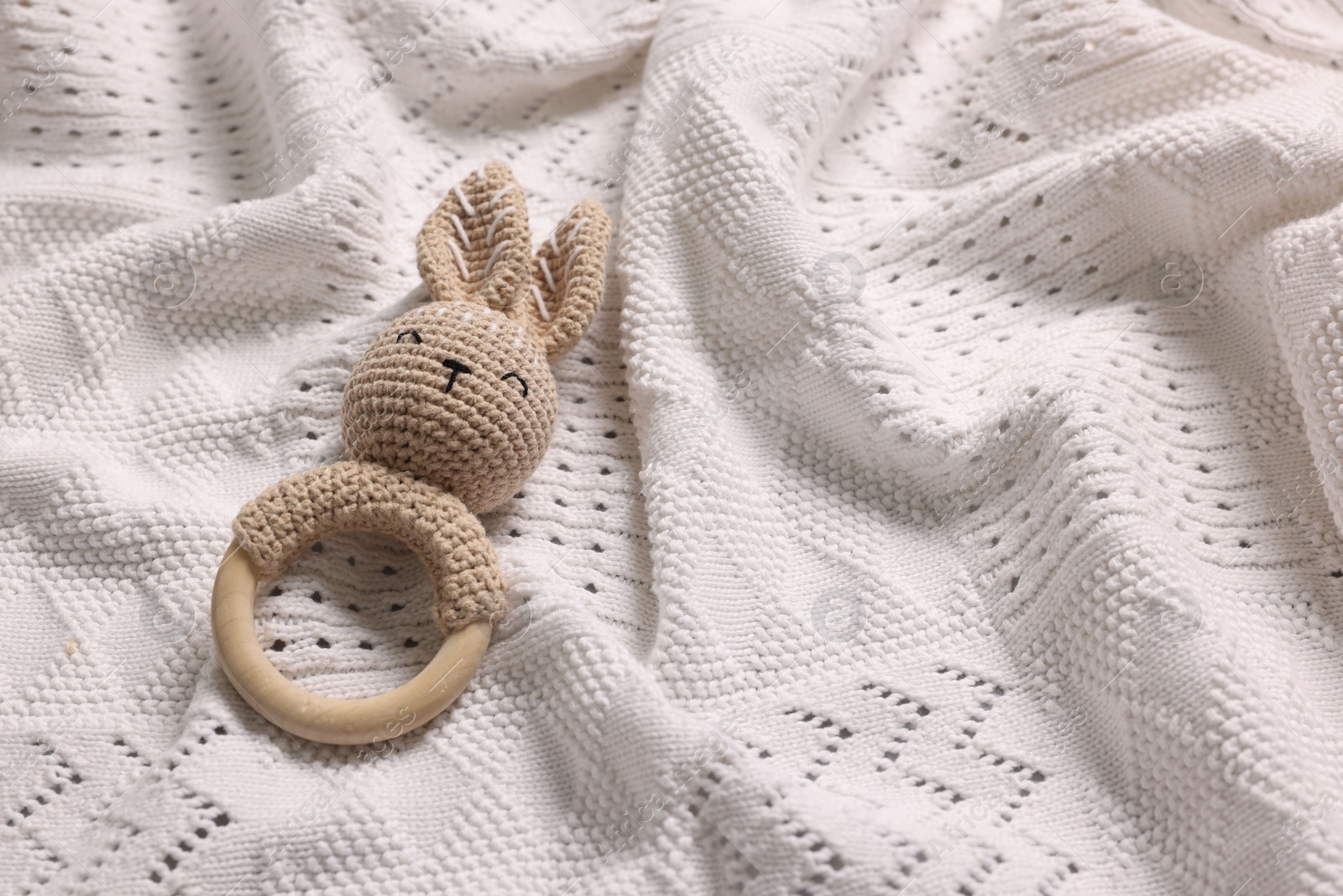 Photo of Baby accessory. Rattle on white knitted fabric, top view. Space for text
