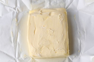 Photo of Piece of tasty homemade butter on paper wrap, top view