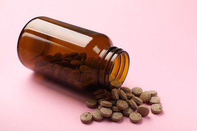 Photo of Bottle and vitamin pills on pink background