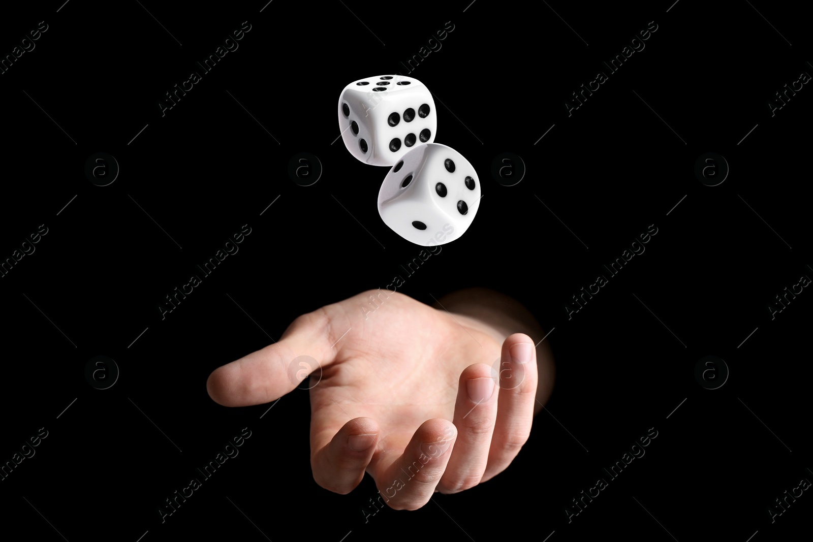 Image of Man throwing white dice on black background, closeup