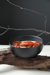 Photo of Delicious boiled crab with cream sauce in bowl on white table. Creative dish presentation