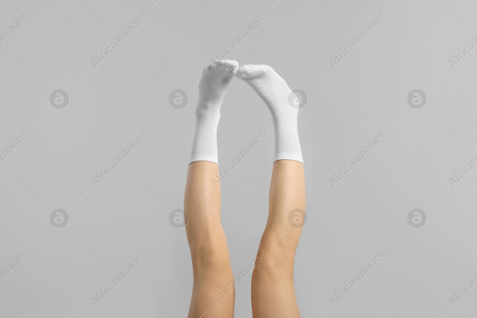 Photo of Woman in stylish white socks on light grey background, closeup