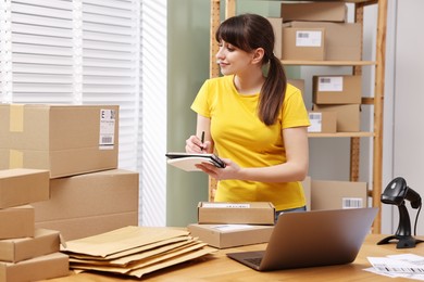 Parcel packing. Post office worker writing notes indoors