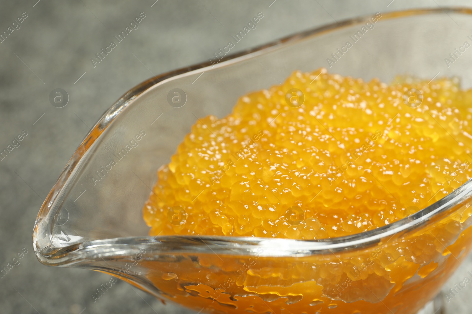 Photo of Fresh pike caviar in gravy boat on table, closeup