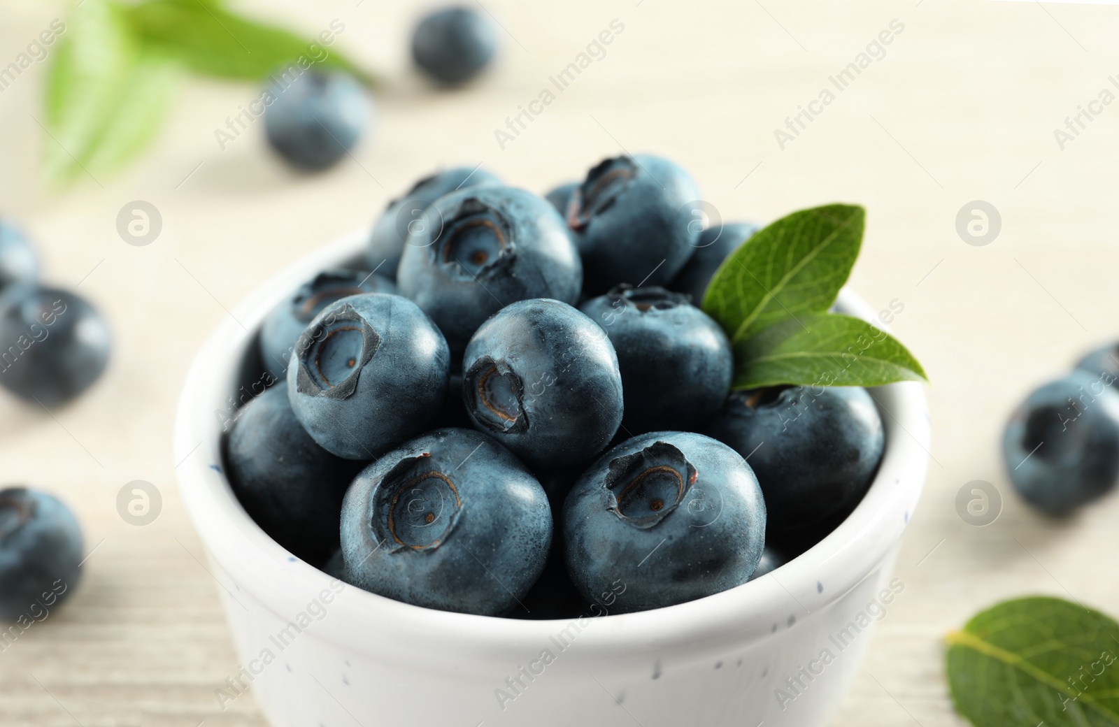 Photo of Bowl of fresh tasty blueberries on table, closeup