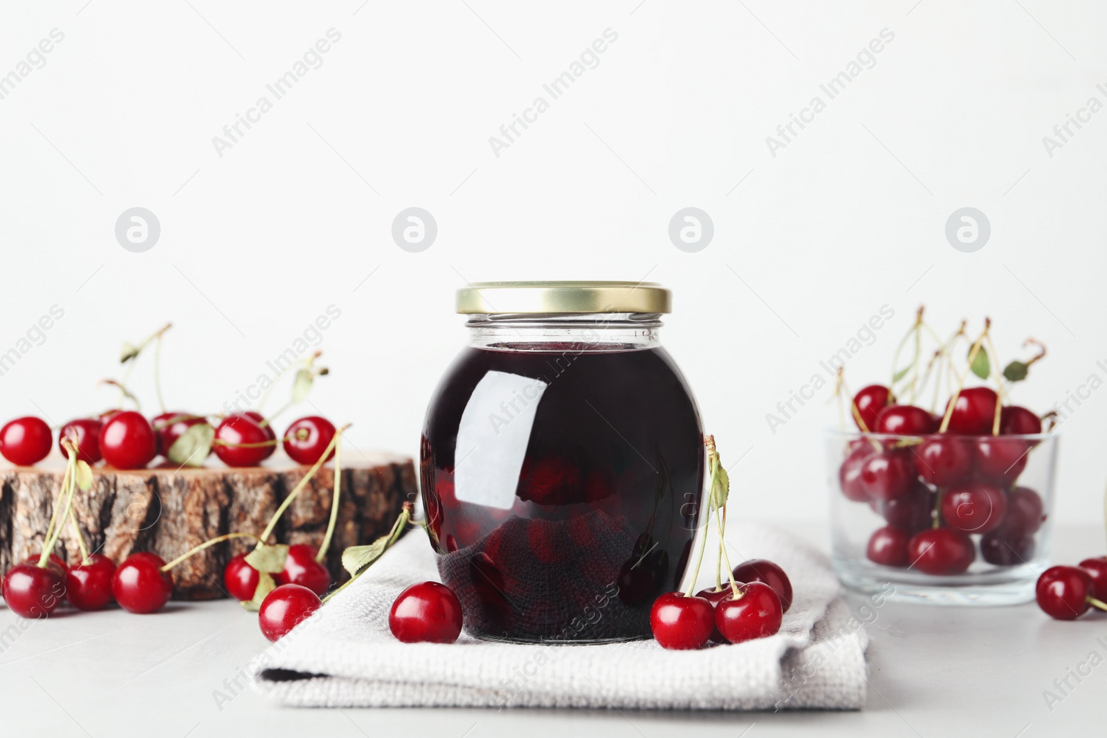 Photo of Jar of pickled cherries and fresh fruits on light table